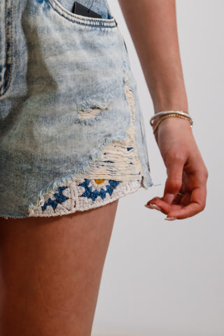 Mid-rise light wash denim shorts with flower embroider detail under rips near bottom