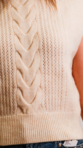 Close-up of a beige cable knit sweater vest