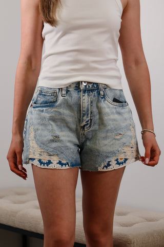Mid-rise light wash denim shorts with flower embroider detail under rips near bottom