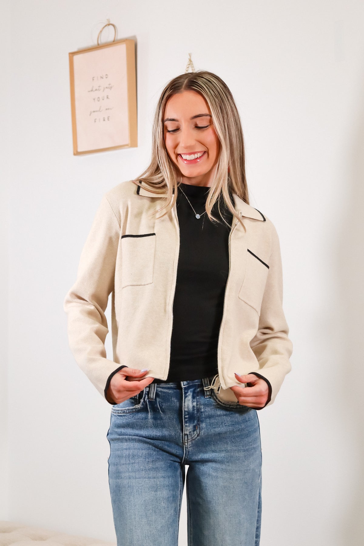 oatmeal color zip up jacket with black trim on the sleeves, pockets, and collar