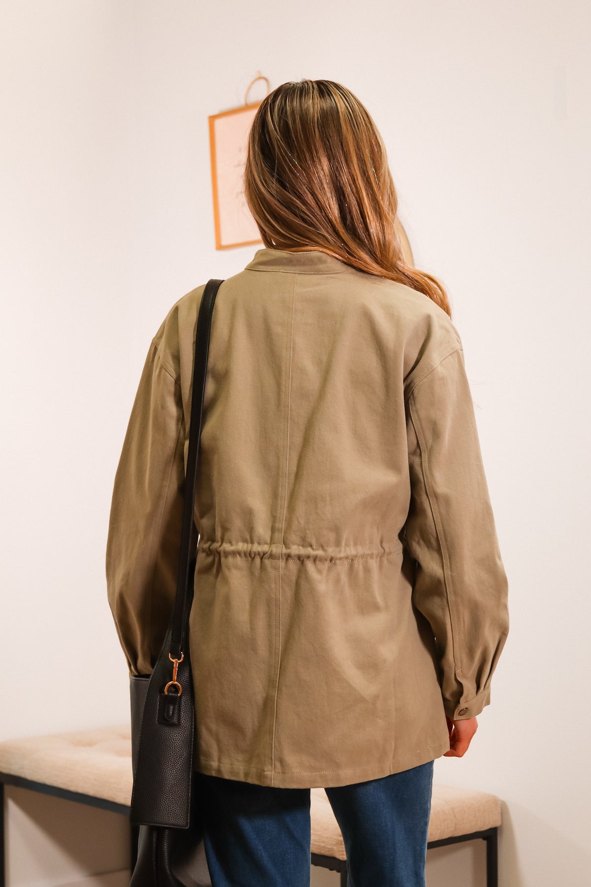 utility women's jacket in olive green with a front zipper, side pockets, and waistline drawstring