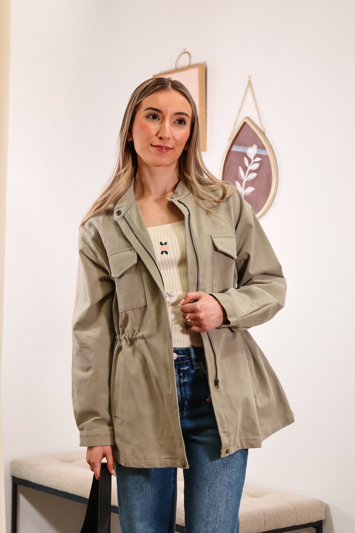 utility women's jacket in olive green with a front zipper, side pockets, and waistline drawstring