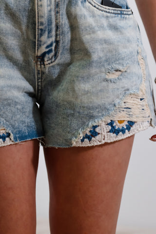 Mid-rise light wash denim shorts with flower embroider detail under rips near bottom